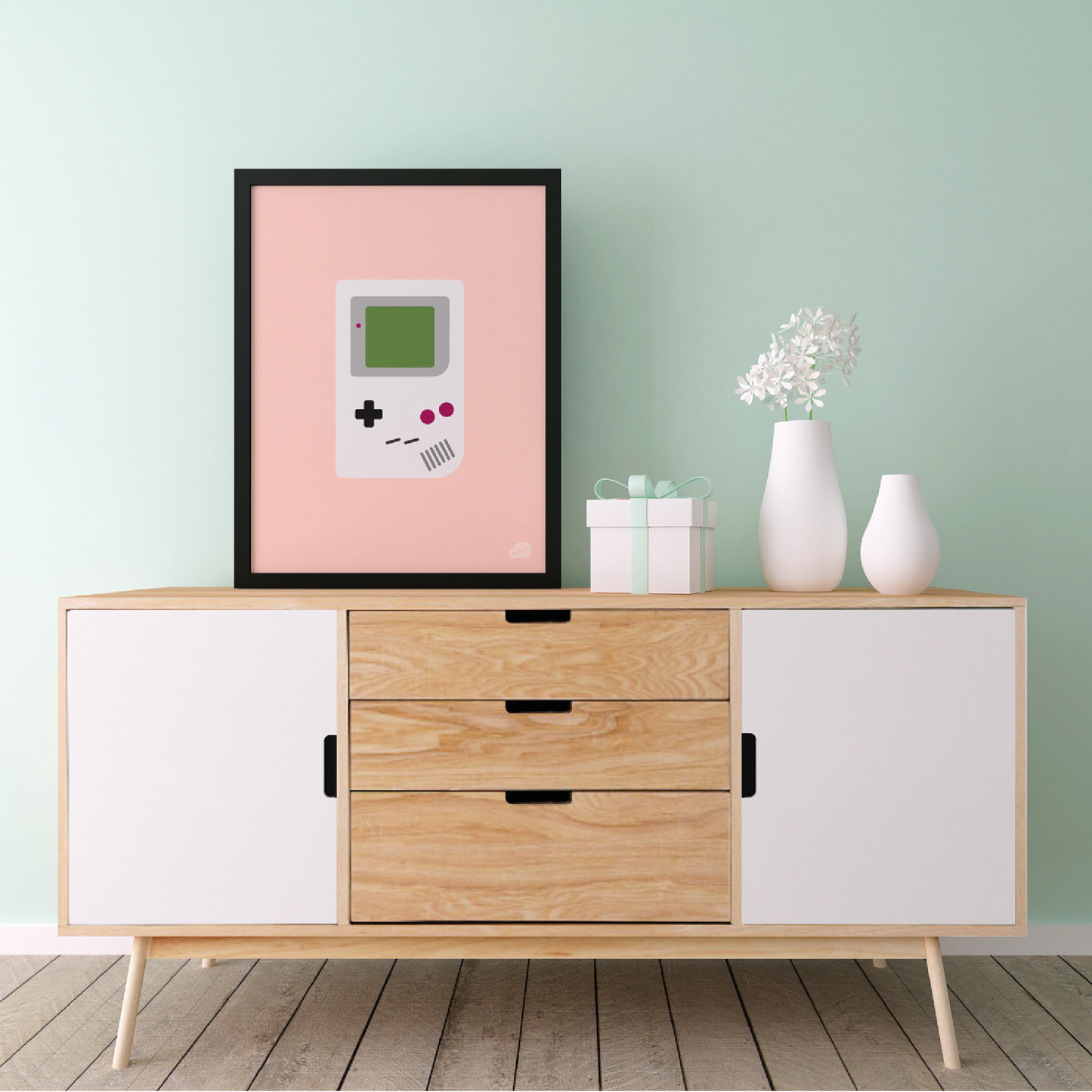 Plakat med game boy med rosa bakgrunn stående på en sjenk