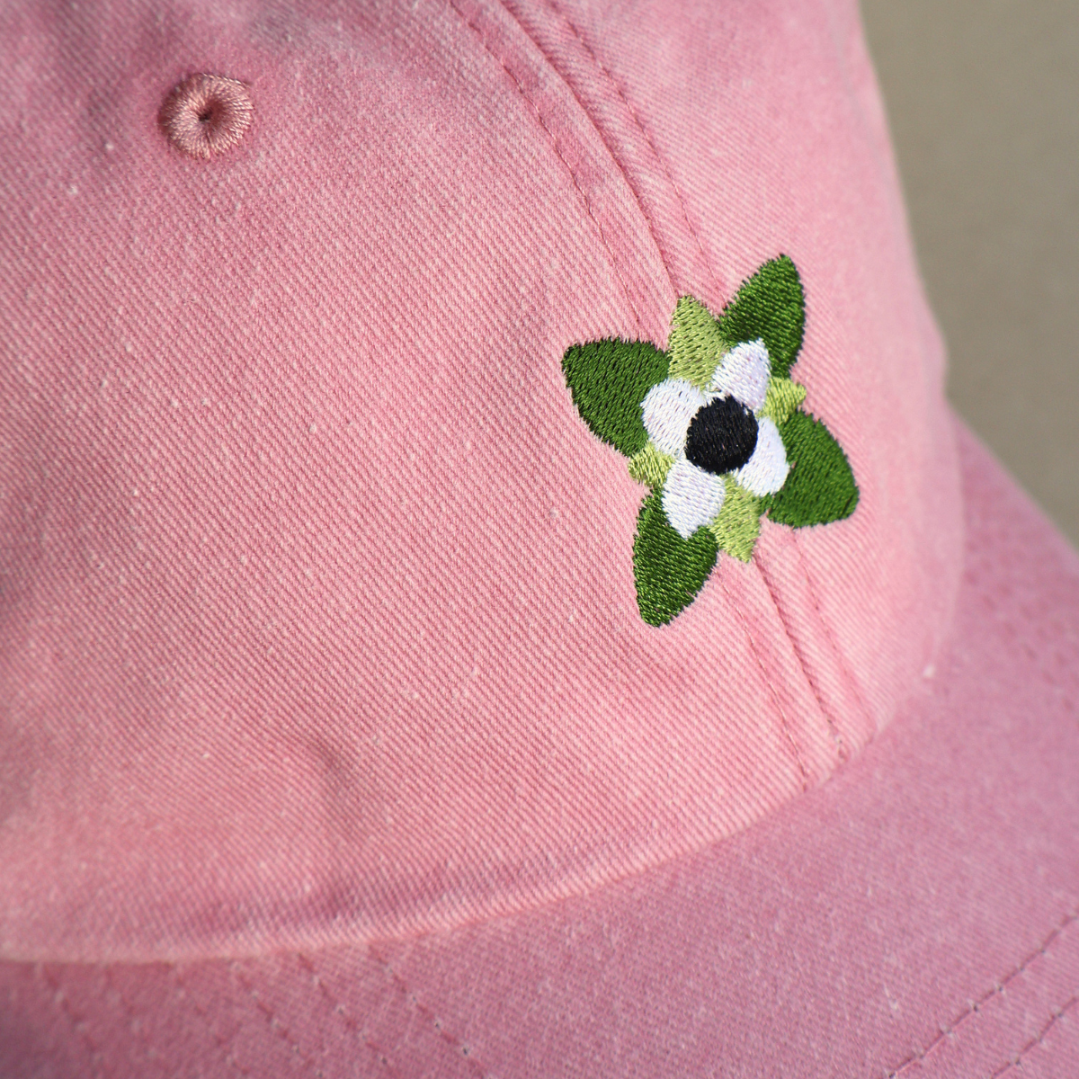 Nærbilde av hvit kaffeblomst brodert på en rosa vasket bomullscaps i vintage stil