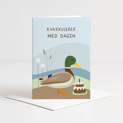 Dobbelt bursdagskort fra Holloi med en illustrasjon av en stokkand ved siden av en bursdagskake, og teksten KVAKKULERER MED DAGEN